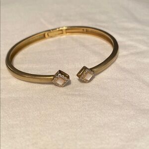 Gold tone hinged bangle with mother of Pearl and diamond accent